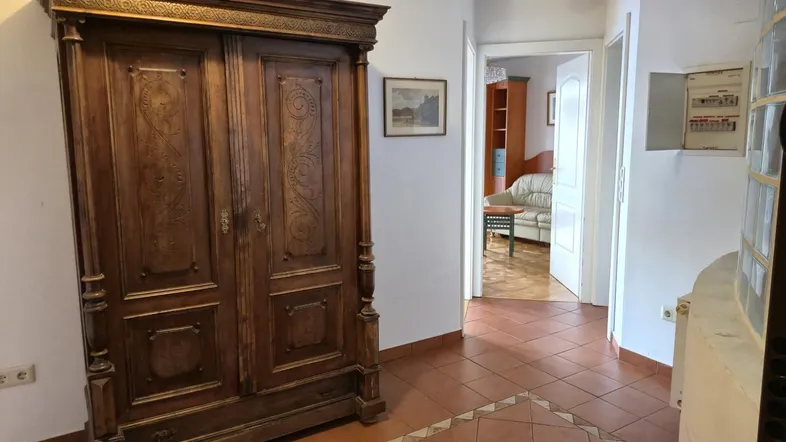 Geräumiger Flur mit traditionellem Holzschrank und Terrakotta-Fliesenboden, der in weitere Räume führt.