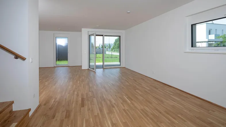 Helles Wohnzimmer mit Holzboden und Zugang zum Garten durch große Terrassentüren.