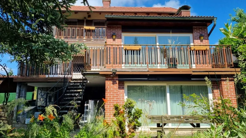 Mehrstöckiges Haus mit Ziegelfassade, mehreren Balkonen und einem gepflegten Gartenbereich.