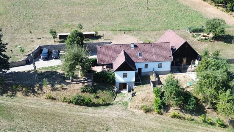 Luftaufnahme eines Anwesens mit Wohnhaus, Nebengebäuden, gepflasterter Auffahrt und weitläufiger ländlicher Umgebung.