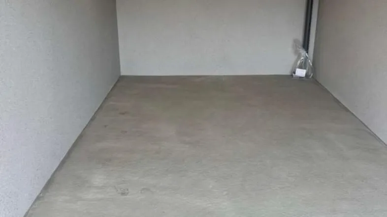 Leerer, sauberer Raum mit Betonboden und einfacher Deckenbeleuchtung, ideal als Lagerfläche.
