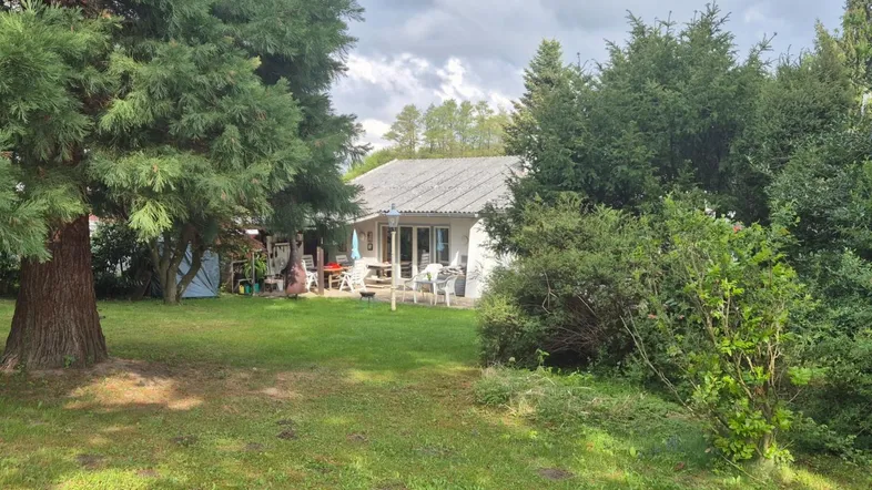 Großer Gartenbereich mit Rasenfläche, altem Baumbestand und einer Terrasse am Haus.