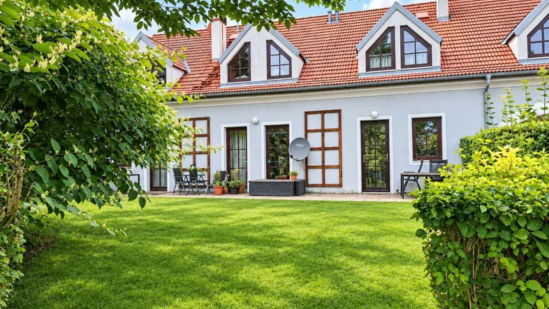 Großer, gepflegter Garten mit Rasenfläche und Sitzgelegenheiten hinter dem Haus.