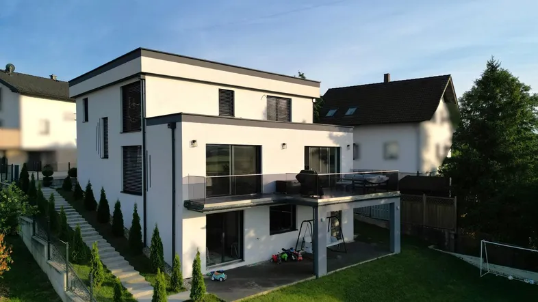Modernes Einfamilienhaus mit Flachdach, großer Terrasse und gepflegtem Gartenbereich.