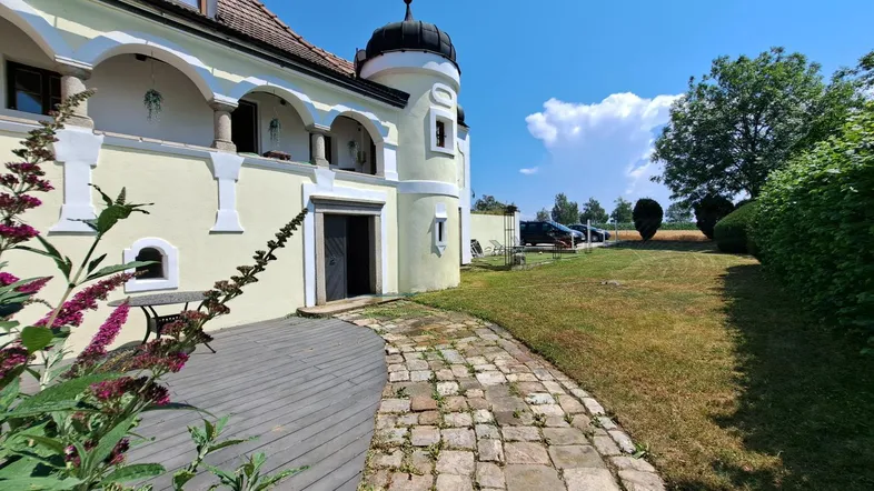 Historisches Gebäude mit charmantem Holzboden-Terrassenbereich und Blick ins Grüne.