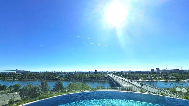 Dachpool mit atemberaubendem Stadtblick, Fluss und Brücke unter strahlendem Sonnenschein.