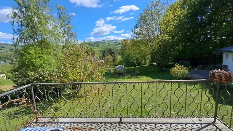 Geräumiger Balkon mit schmiedeeisernem Geländer und weitem Blick ins Grüne und auf die umliegenden Hügel.