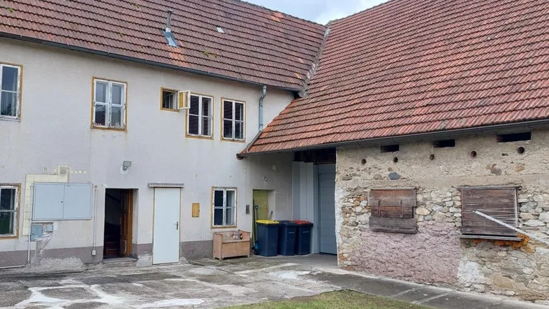 Historisches Gebäudeensemble mit Wohnhaus und angrenzendem Wirtschaftsgebäude unter Ziegeldächern.