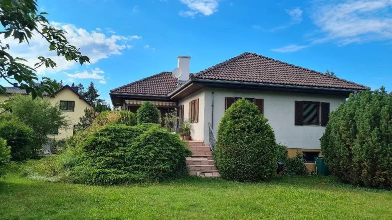 Einfamilienhaus mit gepflegtem Garten und traditioneller Architektur unter blauem Himmel.