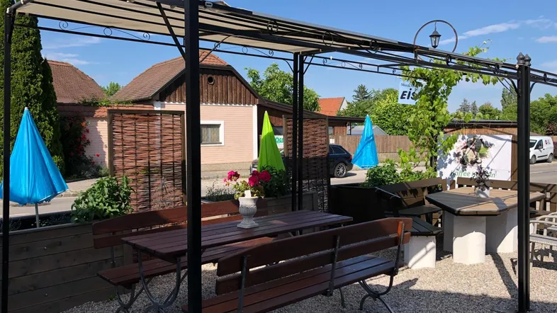 Gemütlicher Außenbereich mit Pergola, Holztischen und Bänken, ideal für entspannte Stunden im Freien.