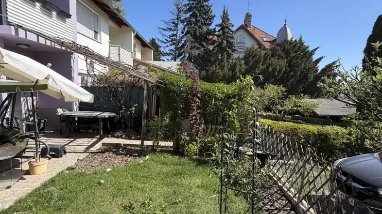 Gepflegter Gartenbereich mit Rasenfläche, Pflanzen und einer Terrasse mit Sitzgelegenheiten.