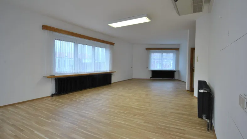 Heller, leerer Raum mit Parkettboden und mehreren Fenstern, bereit zur individuellen Gestaltung.