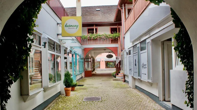Ein charmanter Innenhof mit Kopfsteinpflaster, umgeben von Gebäuden mit Balkonen und Geschäften.