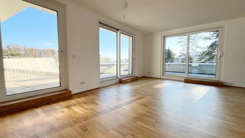 Helles Wohnzimmer mit Parkettboden und großen Schiebetüren zur Terrasse.