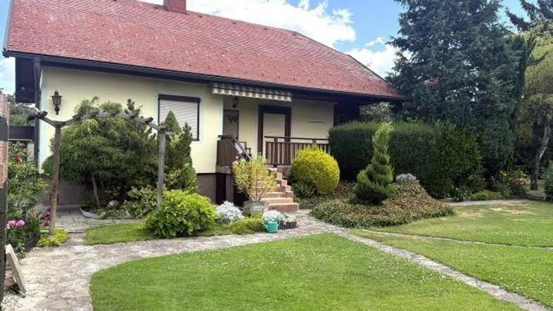 Gepflegter Vorgarten mit Rasenfläche und einem charmanten Einfamilienhaus unter blauem Himmel.