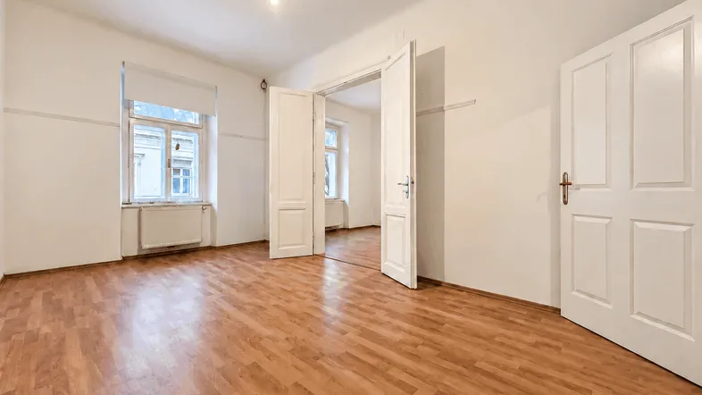 Geräumiger, unmöblierter Wohnraum mit hellem Laminatboden und zwei Fenstern für viel Tageslicht.