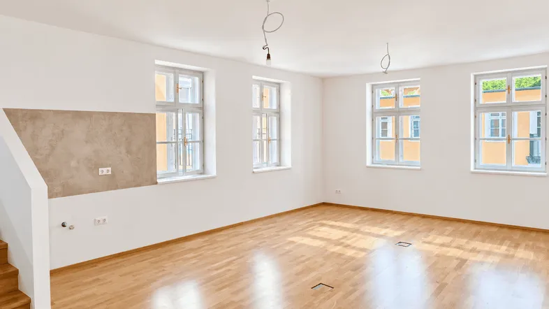 Heller, leerer Raum mit Holzboden und mehreren Fenstern, bereit für die individuelle Gestaltung.