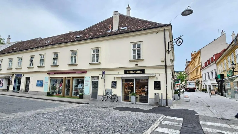 Blick auf eine belebte Straße mit historischen Gebäuden und Geschäften im Erdgeschoss.