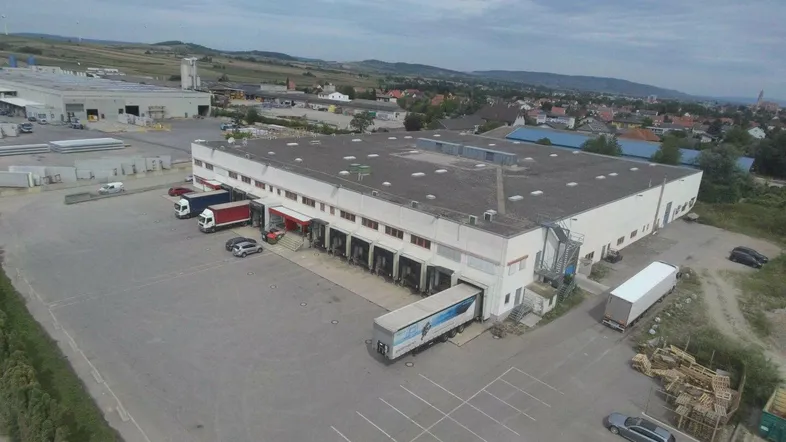 Luftaufnahme eines großen Industriegebäudes mit zahlreichen Laderampen und weitläufigem Parkplatzbereich.