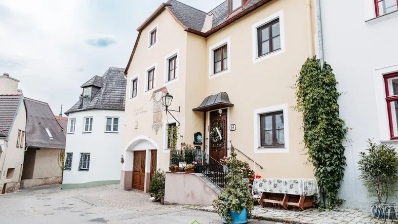 Traditionelles Gebäude mit heller Fassade und charmanten Details an einer ruhigen Straße gelegen.