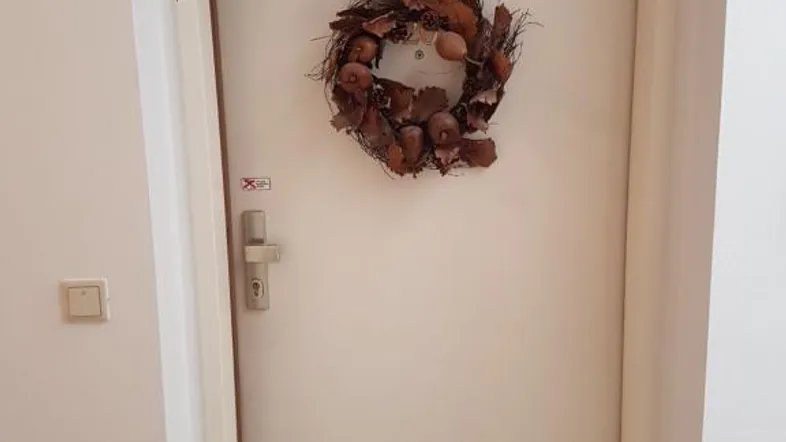 Eingangstür mit herbstlichem Kranz in einem hellen Flur mit Parkettboden.