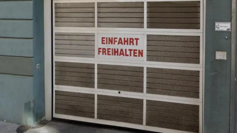 Garageneinfahrt mit Rolltor und Hinweisschild, das auf die Durchfahrtshöhe hinweist.