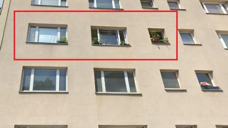 Fassade eines Mehrfamilienhauses mit mehreren Fenstern und Blumenkästen an den Simsen.