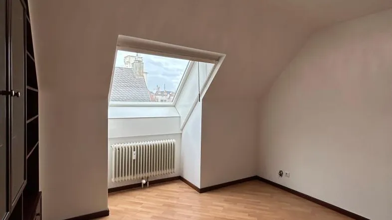 Helles Zimmer im Dachgeschoss mit Laminatboden, großem Dachfenster und Einbauschrank.