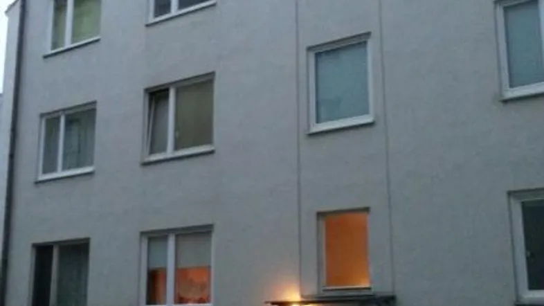 Fassade eines Mehrfamilienhauses mit mehreren Fenstern und dem Eingangsbereich im Erdgeschoss.