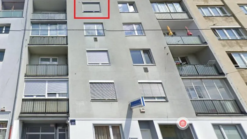 Mehrstöckiges Wohngebäude mit Balkonen und Rollläden in einer städtischen Umgebung.