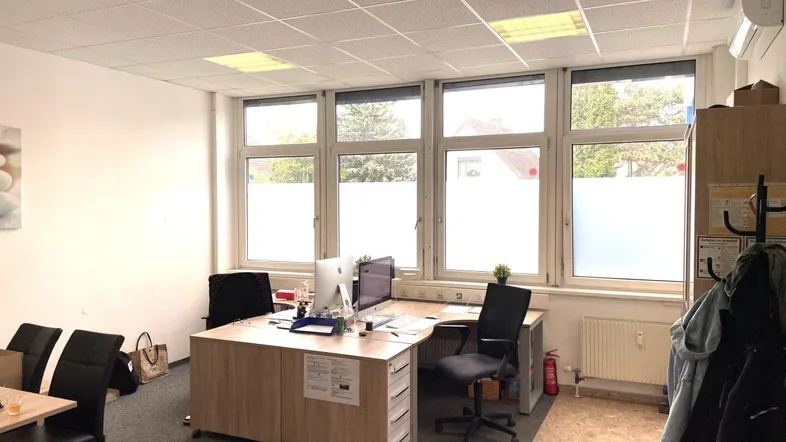 Helles und geräumiges Büro mit mehreren Arbeitsplätzen, großen Fenstern und Klimaanlage.