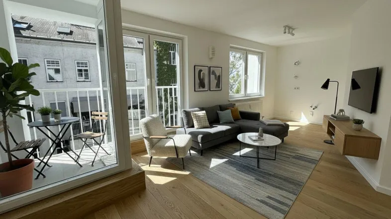 Helles Wohnzimmer mit modernem Sofa, Holzboden und Zugang zu einem kleinen Balkon.