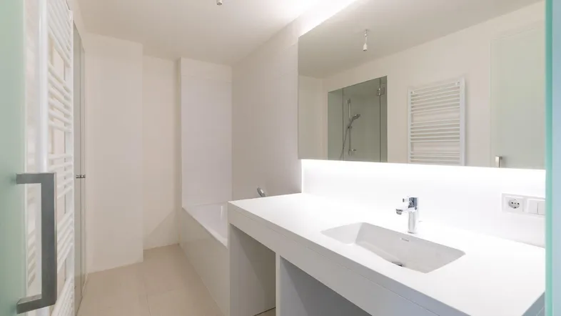 Modernes Badezimmer mit weißem Waschtisch, integriertem Spiegel und Badewanne sowie separater Dusche.