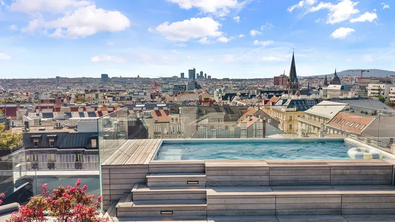 Dachterrasse mit Infinity-Pool und Panoramablick über die Stadt Wien.