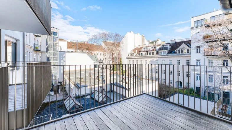 Geräumiger Balkon mit Holzboden und Blick auf die umliegenden Gebäude und Innenhöfe.