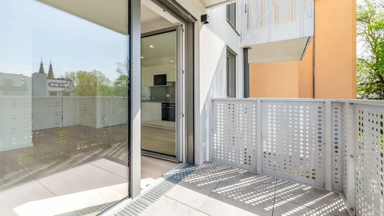Heller Balkon mit modernen Lochblechgeländern und Blick in die offene Küche.