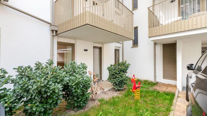 Kleiner Gartenbereich im Innenhof mit Spielgerät und Zugang zu den Wohnungen.