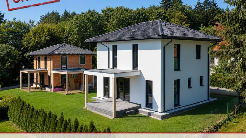 Modernes Einfamilienhaus mit weißer Fassade und Garten, umgeben von viel Grün.