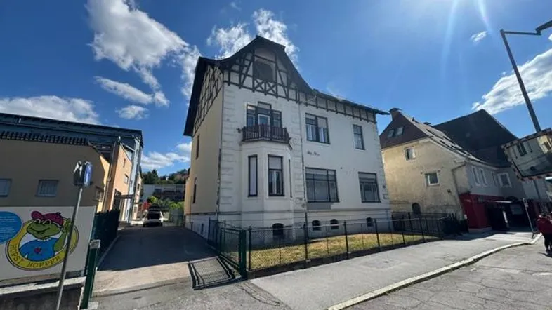 Historisches Gebäude mit markanter Fassade und Mansarddach unter blauem Himmel.