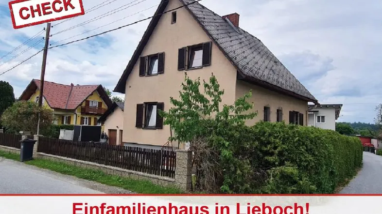 Traditionelles Einfamilienhaus mit Satteldach und braunen Fensterläden, umgeben von einem gepflegten Zaun und Hecke.