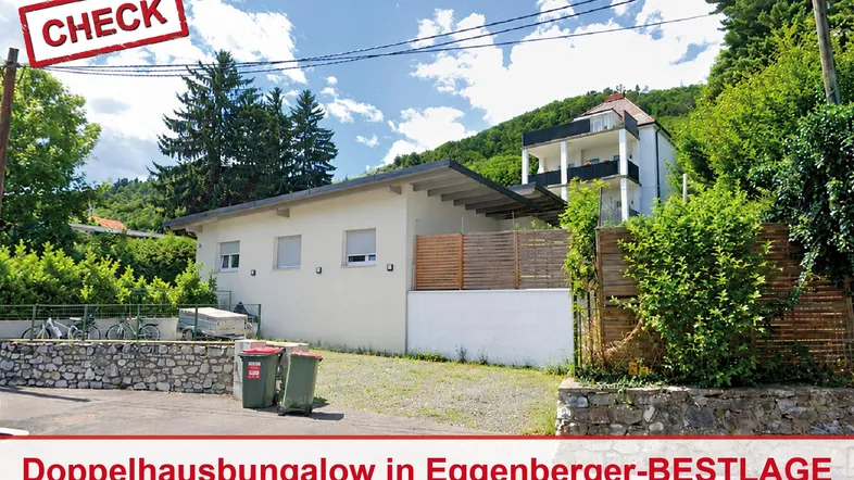 Außenansicht eines modernen Bungalows mit angrenzendem Mehrfamilienhaus in sonniger Lage.