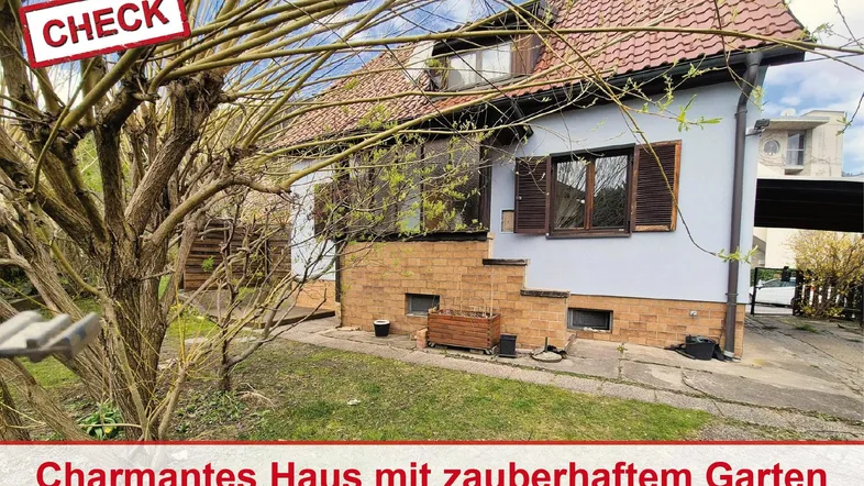 Charmantes Haus mit rotem Ziegeldach und einem gepflegten Gartenbereich im Vordergrund.
