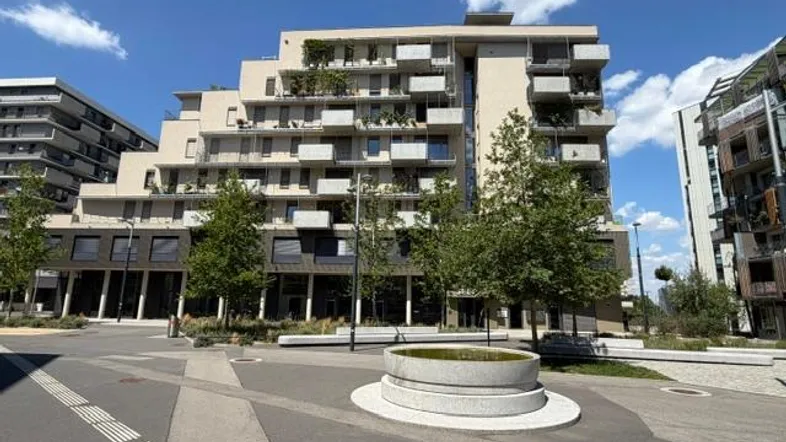 Modernes Wohngebäude mit mehreren Balkonen und begrünten Außenbereichen unter blauem Himmel.