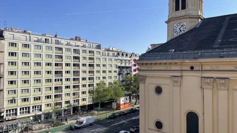 Blick über die Stadtstraße mit historischen Gebäuden und einem Kirchturm unter klarem Himmel.