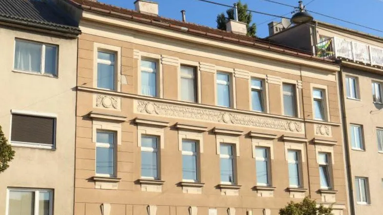 Fassade eines Mehrfamilienhauses mit mehreren Stockwerken und dekorativen Elementen.