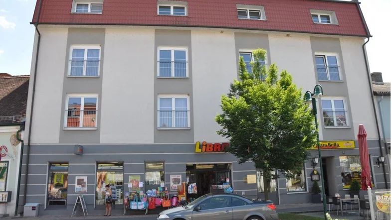 Gebäudeansicht mit Geschäftsflächen im Erdgeschoss und Wohnungen in den oberen Etagen.