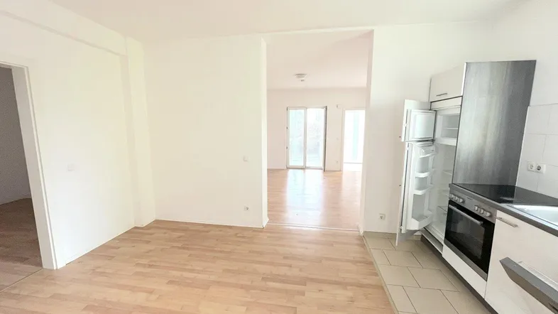 Teilweise ausgestattete Küche mit hellem Holzboden und Blick in den angrenzenden Wohnbereich.