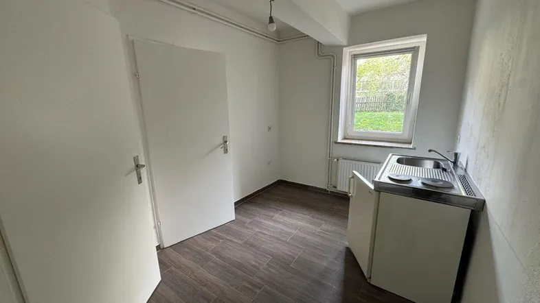 Kleiner Raum mit Kochnische, Fenster und Blick ins Grüne, ideal für ein Studio-Apartment.