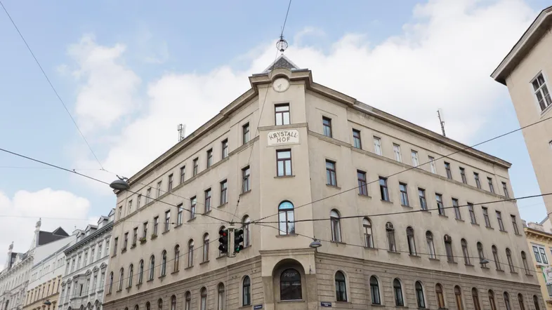 Historisches Eckgebäude "Krystall Hof" mit klassischer Architektur und vielen Fenstern in urbaner Umgebung.