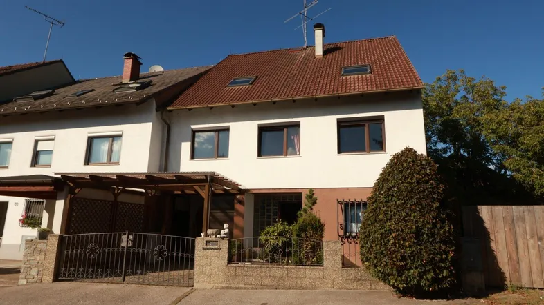 Ansicht des Reihenhauses von vorne mit überdachtem Eingangsbereich und kleinem Vorgarten.